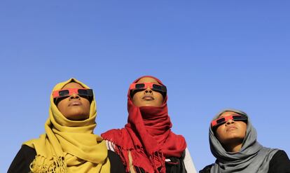 Jartum, Sudán, 3 de noviembre de 2013. Tres mujeres observan el eclipse de sol híbrido, un peculiar fenómeno que comienza como eclipse anular (con un anillo de disco solar alrededor de la Luna oscura) y acaba como eclipse total, con el Sol completamente oculto.