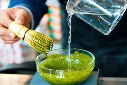 Una persona elabora té matcha con un batidor de bambú y agua caliente.