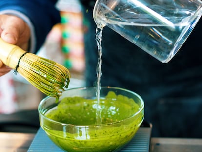 Una persona elabora té matcha con un batidor de bambú y agua caliente.