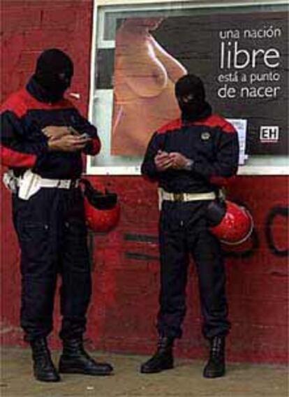 Dos <i>ertzainas</i>, ante un cartel electoral de Euskal Herritarrok el pasado abril.