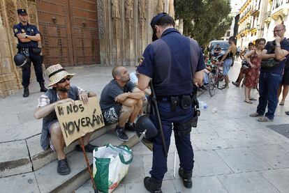 Un agente, junto a varios indignados ayer en la plaza del Ayuntamiento de Valencia.