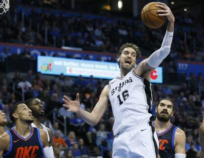 El pívot de los San Antonio Spurs Pau Gasol (16) coge un rebote entre el escolta de los Oklahoma City Thunder André Roberson (izquierda) y el pívot Steven Adams, en el segundo cuarto de un partido de baloncesto de la NBA en Oklahoma City, el domingo 3 de diciembre de 2017.