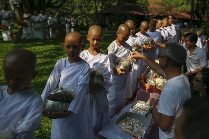 Novice nuns receive food from people during the Songkran Festival at the Sathira-Dhammasathan Buddhist meditation centre in Bangkok, Thailand, April 13, 2016. REUTERS/Athit Perawongmetha