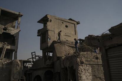 Trabajadores caminan sobre lo alto de los edificios y tiendas dañadas en la Ciudad Vieja de Mosul.