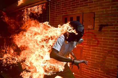 La imagen ganadora del World Press Photo 2018 muestra a José Salazar, 28 años, corriendo mientras las llamas consumen su cuerpo durante una protesta en Caracas contra el Gobierno de Nicolás Maduro, el 3 de mayo de 2017. Tras el nombramiento de los 'magistrados exprés' y el veto del Tribunal Supremo de Justicia (TSJ) contra la Asamblea Nacional de Venezuela, en marzo de 2017 se iniciaron protestas diarias que alcanzaron los 100 días de manifestaciones en el país. Durante este período, 91 personas murieron, 1.413 resultaron heridas, 5.000 fueron detenidas y se amenazó a los alcaldes y gobernadores opositores con cárcel si no dejaban de participar en las calles. El clima de máxima tensión se vivió durante las elecciones a la Asamblea Nacional Constituyente auspiciada por el régimen de Nicolás Maduro. Desde el 1 de abril, el Observatorio Venezolano de Conflictividad Social (OVCS) contabilizó un total de 6.729 protestas en todo el país y 163 muertes. Las manifestaciones perdieron impulso a medida que el Gobierno fue concediendo peticiones de la de oposición como la liberación de algunos presos políticos.