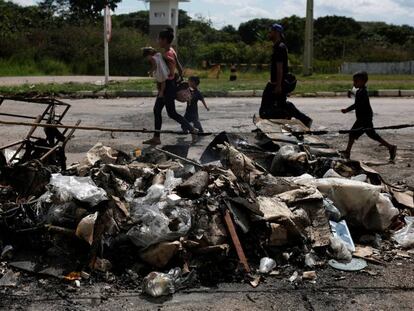 Uma família de venezuelanos passa pelos seus objetos pessoais incendiados por brasileiros na fronteira de Pacaraima (Roraima).
