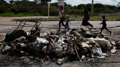 Uma família de venezuelanos passa pelos seus objetos pessoais incendiados por brasileiros na fronteira de Pacaraima (Roraima).