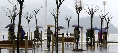 Donostiarras y turistas se protegen con sus paraguas en el paseo de la Concha, en San Sebastián, en una jornada lluviosa de la pasada Semana Santa.