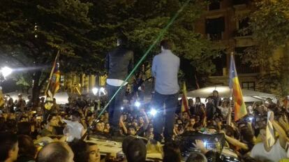 Los líderes de ANC y Ómnium, Jordi Sànchez y Jordi Cuixart, subidos en el techo de un coche de la Guardia Civil durante las protestas por los registros ordenados por un juez en la Consejería de Economía.