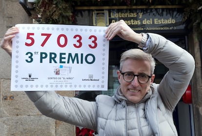 El propietario de la administración número tres de Santiago de Compostela, José Luis Tojo, muestra el número agraciado con el tercer premio de El Niño, cuyos décimos ha vendido él por ventanilla.
