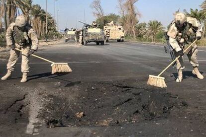 Dos soldados estadounidenses limpian un tramo de asfalto donde un conductor suicida atacó a una patrulla militar ayer en Bagdad.