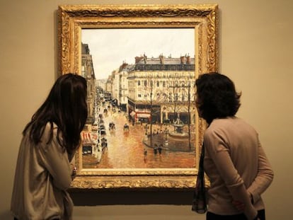 Dos visitantes observan el cuadro 'Rue Saint-Honoré por la tarde. Efecto de lluvia', de Pisarro, en el Museo Thyssen de Madrid.