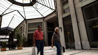 Dos hombres caminan por un centro comercial en Atenas.