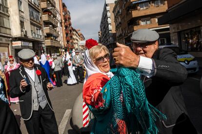 Varias personas vestidas con los trajes típicos de chulapos bailan en las calles de Madrid. 
