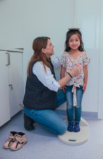 Una trabajadora de Guatemaltecos por la Nutrición mide la estatura de una niña.