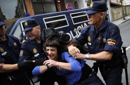 Agentes de la policía detienen a una activista de Stop Desahucios.