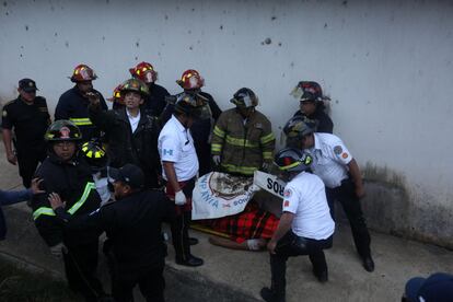 Bomberos guatemaltecos permanecen junto al cuerpo de uno de los monitores fallecidos en un centro de menores.