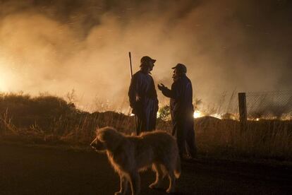 Dos vecinos, junto a las llamas, comentan el desastre en Cualedro.