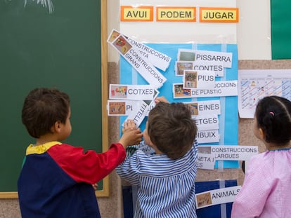Tres niños juegan con letreros en catalán en un aula de Infantil de tres años.