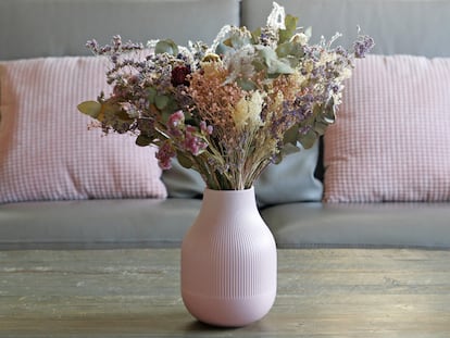 Un jarrón rosa con flores artificiales.