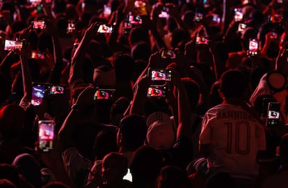 Aficionados graban con sus teléfonos móviles la ceremonia de apertura desde una pantalla que proyecta lo que ocurre dentro del estadio en la zona del Fest Fan en Doha.