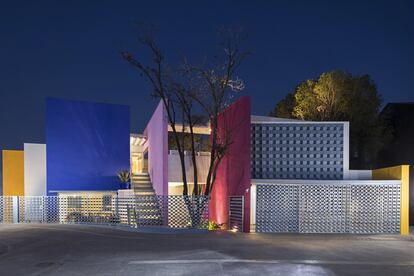 Componen la fachada una celosía de hormigón y dos muros de colores que enmarcan la entrada. El acero con que está hecha la valla exterior es tan  ligero que parece de encaje. En el jardín exterior se alza un enorme nogal