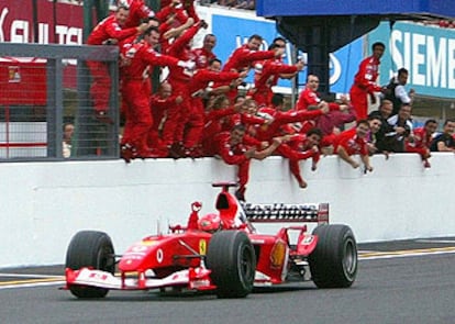 Michael Schumacher da la vuelta de honor al circuito de Suzuka entre el entusiasmo de los miembros de su equipo,  Ferrari, campeón también por marcas.