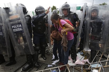 Una madre y un niño migrantes hondureños se encogen de miedo al ser rodeados por la Policía Federal Mexicana en un motín antidisturbios, en el cruce fronterizo de Ciudad Hidalgo (México), el 19 de octubre de 2018.