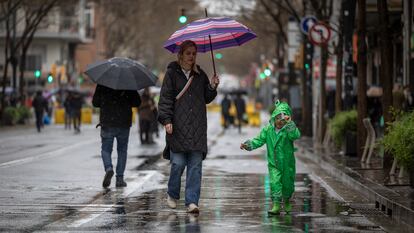 Varias personas caminan bajo la lluvia con sus paraguas por carretera de Sants.