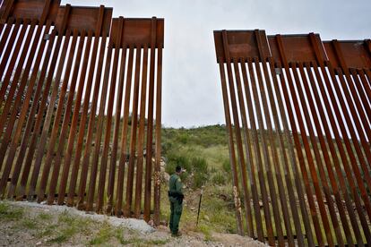 El agente Jesus Vasavilbaso mira hacia México a través de una apertura en el muro fronterizo en la que nunca se instaló una puerta, debido al alto en los trabajos de construcción.