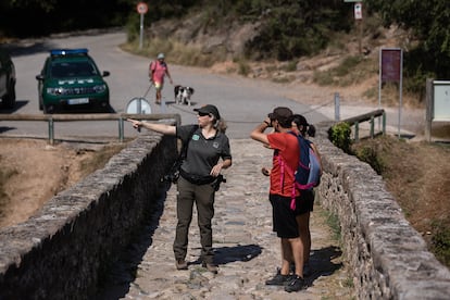 Una agente rural de la comarca del Berguedà conversa con una pareja de senderistas en el Pont del Pedret, en verano de 2022, durante la campaña de prevención de incendios forestales.