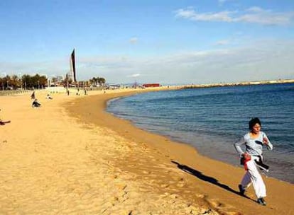 Una mujer corre por una playa de Barcelona