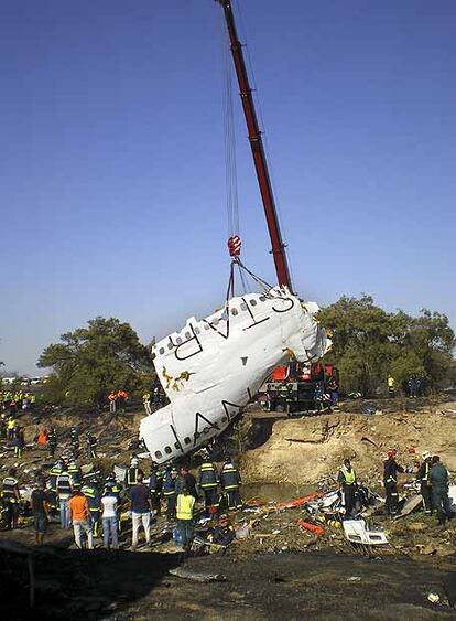 Una grúa recoge parte del fuselaje del avión siniestrado.