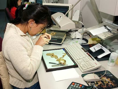 Una empleada de un monte de piedad analiza unas piezas de oro.