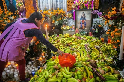 Una mujer acomoda su ofrenda frente al altar dedicado a una familiar en el panteón de Santa Fe de la Laguna, en el Estado de Michoacán.