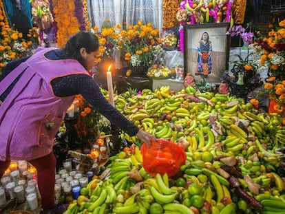 Una mujer acomoda su ofrenda frente al altar dedicado a una familiar en el panteón de Santa Fe de la Laguna, en el Estado de Michoacán.