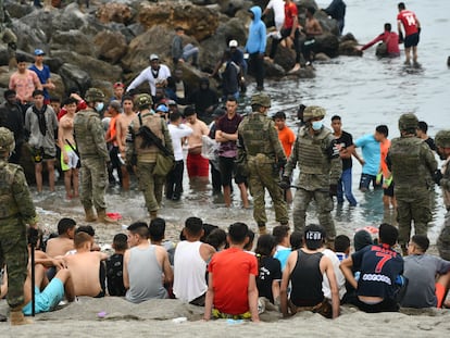 Militares del ejército español vigilan a migrantes, la mayoría de ellos jóvenes, en Ceuta, el 18 de mayo de 2021