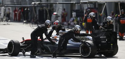 Los mecánicos empujan el coche averiado de Alonso.