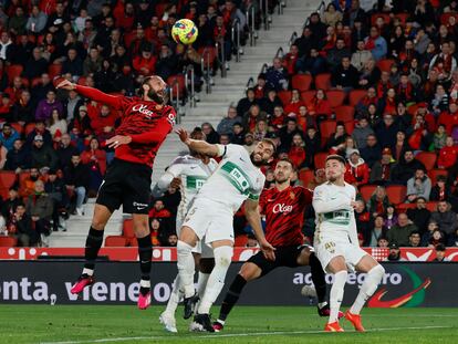 PALMA DE MALLORCA, 04/03/2023.- El delantero del Mallorca Vedat Muriqi (i) salta a por un balón ante Gonzalo Verdú (c), del Elche, durante el partido de Liga en Primera División que RCD Mallorca y Elche CF disputan este sábado en el estadio de Son Moix, en Palma de Mallorca. EFE/Cati Cladera
