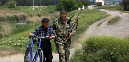 Un rebelde prorruso ayuda a un hombre junto a un control en Slaviansk.