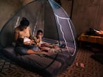 Una mujer amamanta a su bebé dentro de una mosquitera para protegerse el mosquito que transmite la malaria.