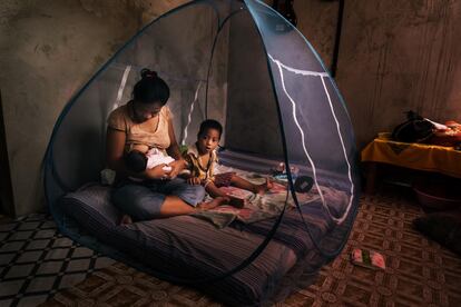 Una mujer amamanta a su bebé dentro de una mosquitera para protegerse del mosquito que transmite la malaria.