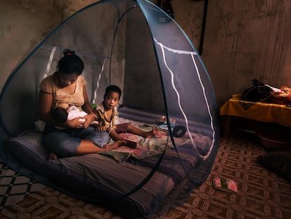 Una mujer amamanta a su bebé dentro de una mosquitera para protegerse del mosquito que transmite la malaria.