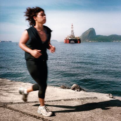 Bahía de Niteroi, a las afueras de Río. Una mujer corre delante de una plataforma petrolífera y el cerro del Pan de Azúcar.