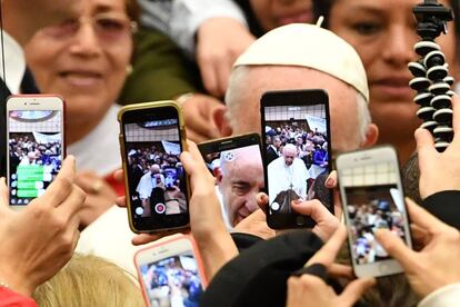 Varias personas a poca distancia del Papa lo encuadran con sus teléfonos móviles.