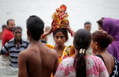 Una mujer carga una figura de la diosa hindú Durga para sumergirse en el río Ganges tras la celebración del último día del festival Navrati en Koljata (India).