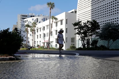 A woman walks along a flooded street in Miami Beach