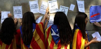 J&oacute;venes con esteladas pegan carteles de apoyo al refer&eacute;ndum. 