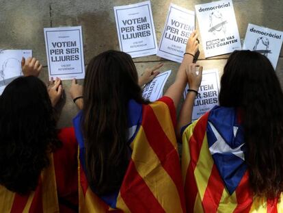 J&oacute;venes con esteladas pegan carteles de apoyo al refer&eacute;ndum. 