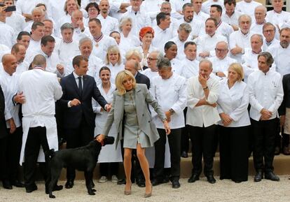 Emmanuel Macron mira a su mujer Brigitte Macron mientras ella trata de apartar su perro Nemo durante una foto de grupo con los mejores chefs franceses en el Palacio del Elíseo, el 27 de septiembre de 2017.  